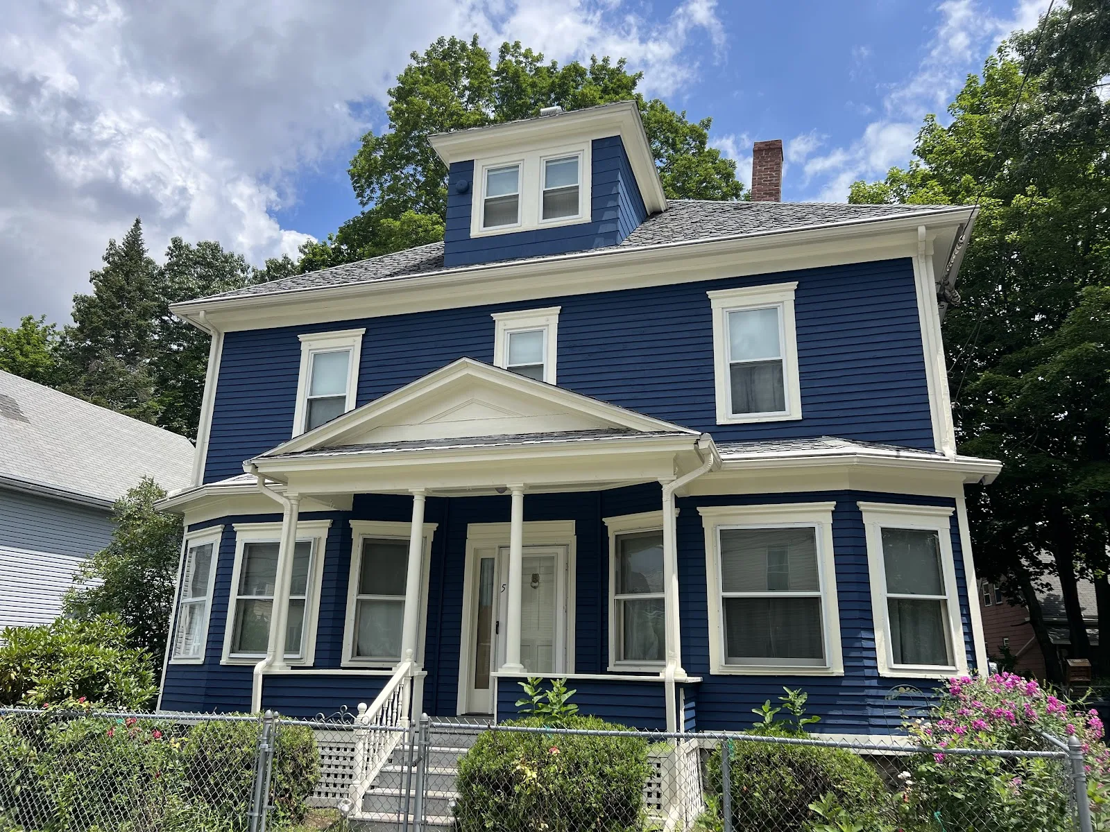 Classic New England colonial repainted deep navy blue with crisp cream trim by Color Life Painting.